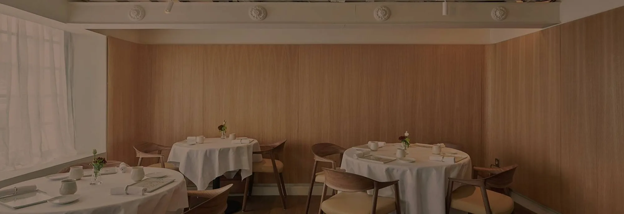 Salle à manger boisée du restaurant, tables rondes nappées de blanc