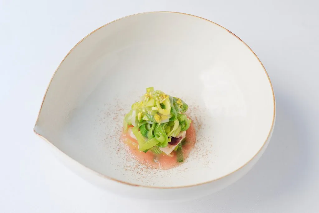 Assiette creuse : coulis rosé, rubans de légumes verts et fleurs jaunes