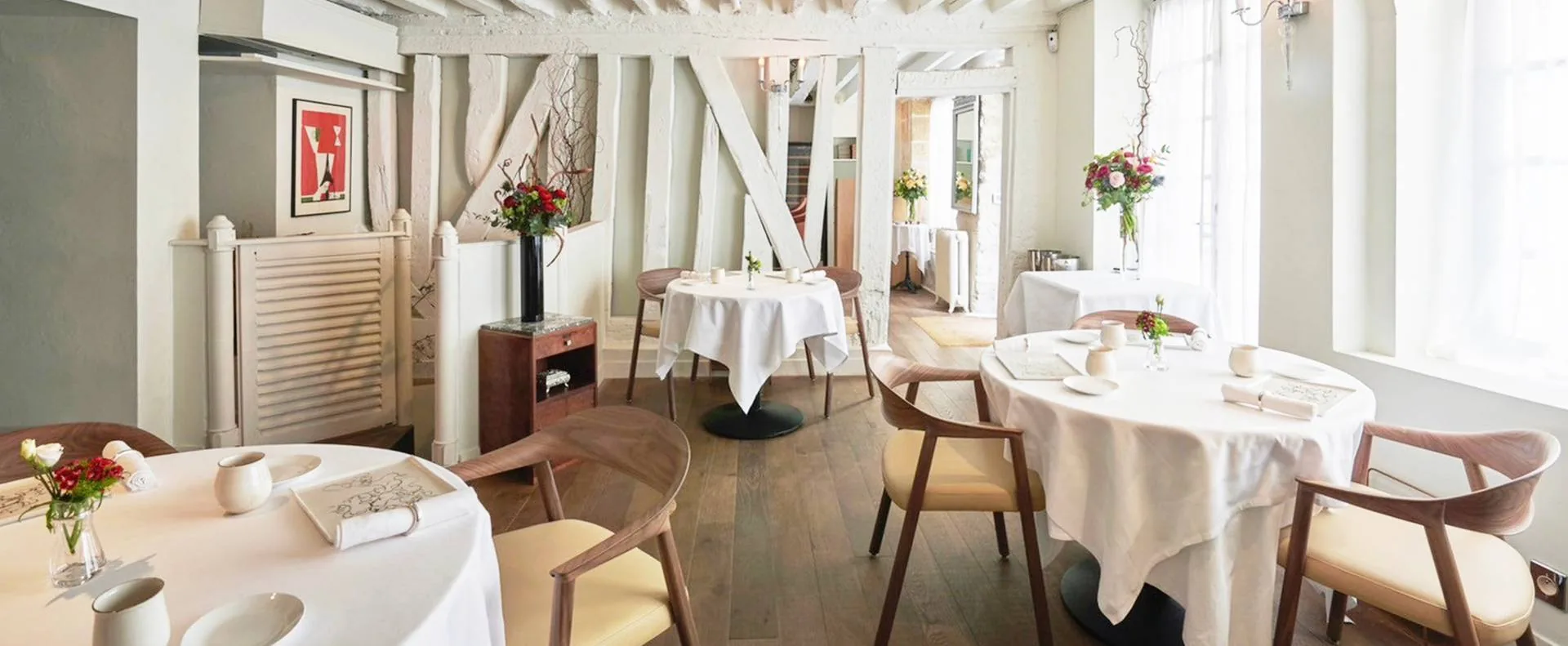 Salle du restaurant : tables nappées de blanc sous les poutres apparentes